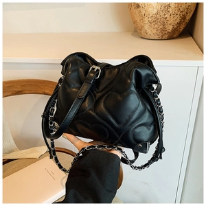 Detail of black heart-quilted shoulder bag with metal buckle and chain leather strap