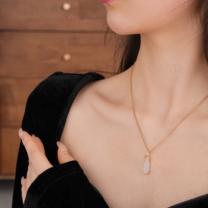 Detail of gold plated necklace featuring a pink chalcedony teardrop pendant on model