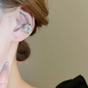 Detail shot of a silver snowflake ear cuff with zircons worn on the cartilage ear
