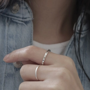 Detail of stacked 925 silver star ring and braided band worn on person's finger