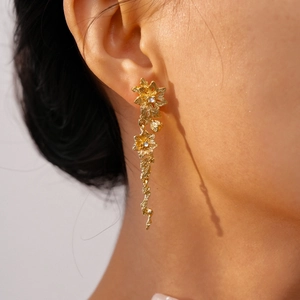 Detail of gold floral dangle earrings with crystals worn by a model in soft lighting