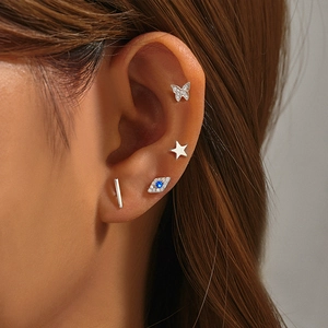 Close-up of a 925 sterling silver butterfly and star stud earring set on a model ear