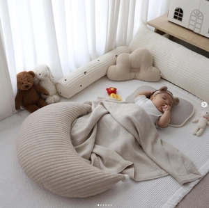 Detail of waffle-textured moon pillow and soft cotton bedding for newborn comfort