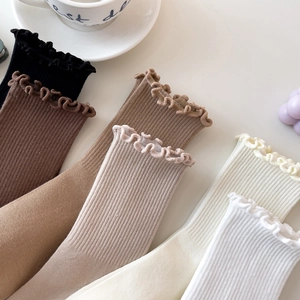 Detail of ruffled cuffs on cotton ribbed socks in various warm neutral earth tones