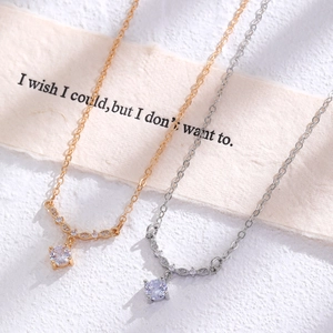 Detail of silver and gold necklaces with round cubic zirconia pendants on white background