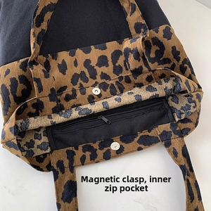 Detail view of the leopard print tote bag showing the magnetic buckle and inner zip pocket