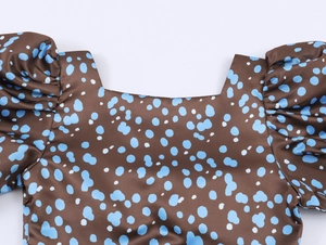 Close-up of brown satin dress featuring blue polka dots and elegant puff sleeve details