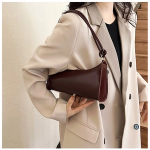 Detail of dark red leather baguette bag with knotted shoulder strap shown on a model