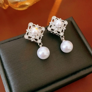 Close-up of diamond-encrusted hollow diamond earrings with elegant white pearl drops