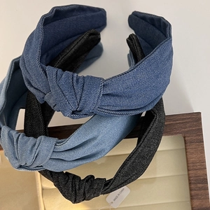 Detailed view of three knotted denim headbands in dark blue, light blue, and black colors