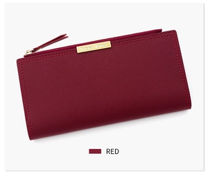 Détail du portefeuille long rouge avec texture cuir, zip doré et plaque logo en métal