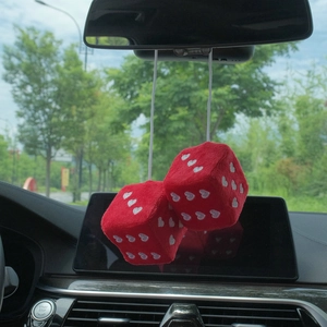 Red plush car dice with white heart dots hanging on a car rearview mirror