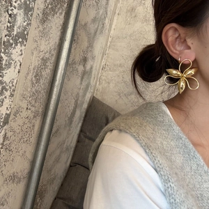 Detailed view of large gold-plated hollow flower earrings on model with metallic finish