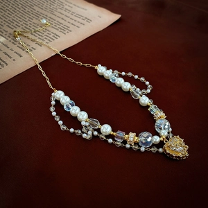 Detail of layered pearl and crystal necklace with a golden heart pendant on vintage paper