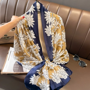 Navy blue and gold floral silk scarf for women styled on a luxury leather background