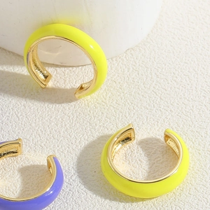 Detail view of colorful enamel C-shape cuff earrings in neon yellow and purple tones