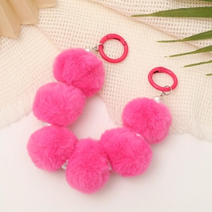Detail showing pink plush pompom beads with white pearls and circular hooks for bags