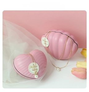 Pink shell jewelry box with elegant gold chain pearl necklace and floral decor