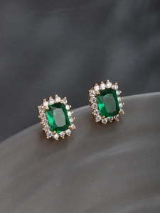 Macro shot of square emerald earrings with sparkling white zircon halo on gold plating