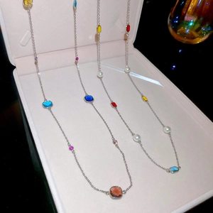 Close-up of stacked stainless steel necklaces with pearls and square crystals in a box
