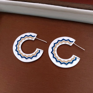 Dettaglio degli orecchini vintage a forma di C con motivo smaltato blu e marrone