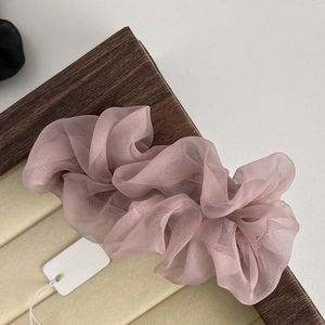 Detailed macro shot of soft pink pleated mesh scrunchie accessory on a wooden tray