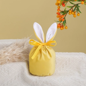 Detail of yellow velvet Easter bunny ear gift bag with ribbon on textured knit mat