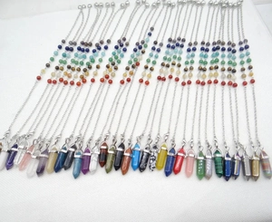 Macro-opname van zeshoekige kristallen hangers met chakra-kralen aan zilveren kettingen