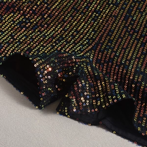 Détail de paillettes irisées haute densité sur un body de Noël en maille noire