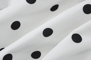 Detailed view of the classic black and white polka dot pattern on woven dress fabric