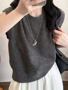 Gros plan sur le collier pendentif peigne argenté sur un pull en maille gris