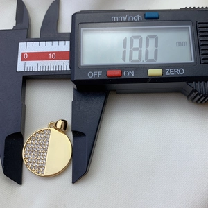 Macro shot showing an 18.0mm diameter measurement of a gold zircon round pendant with caliper