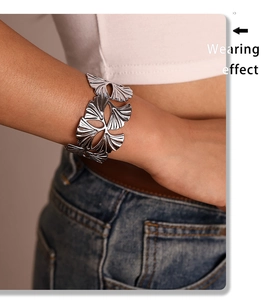 Detail view of silver hollow ginkgo leaf cuff bracelet worn on female wrist for style