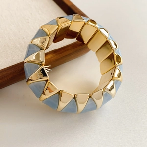 Close-up of geometric gold-tone bracelet with light blue enamel triangles and elastic fit