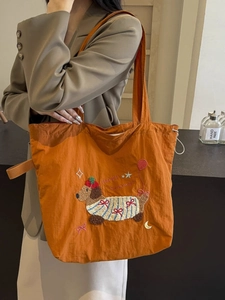 Large orange canvas tote bag with Happy Summer embroidery shown on a model's shoulder