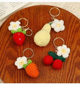 Detail of four handmade crochet fruit and vegetable keychains on a wooden plate