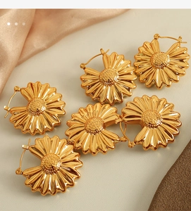 Macro shot of gold floral earrings with glossy petal finish on luxury champagne satin