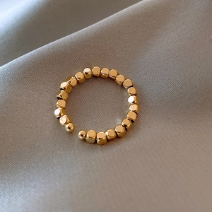 Dettaglio anello aperto a sfere geometriche placcato oro 14k su seta grigia