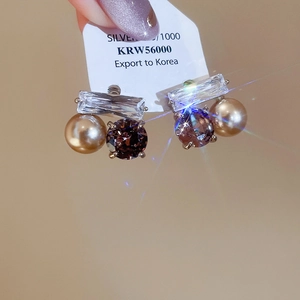 Détails macro de boucles d'oreilles en argent avec zircon carré, perle et œil de tigre brun