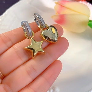 Detailed view of asymmetric gold heart and star earrings with sparkling zircon inlay
