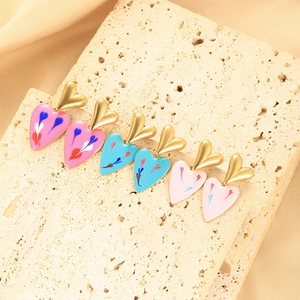 Detailed view of three pairs of colorful heart drip oil earrings on a stone plate