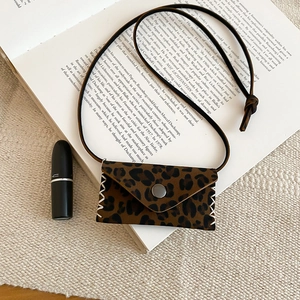 Macro shot of leopard print mini bag pendant with silver snap button and hand-stitched edges