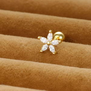 Macro detail of a gold flower stud earring with zircon petals in a brown velvet box