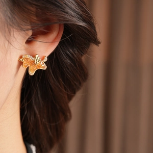 Close-up of golden ginkgo leaf earrings with orange inlay and zircon details on ear