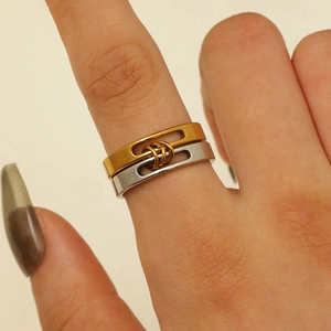 Detail of interlocking gold and silver layered wide bands with cutout slots on the finger
