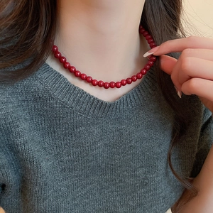 Close-up of deep red glass beaded necklace worn by a model on a grey sweater