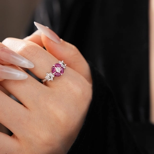 Detailed close-up of a sparkling ruby flower ring set in silver on a model's finger