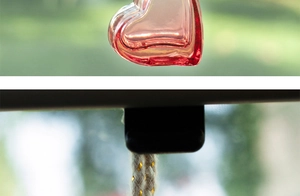 Detail of heart-shaped glass bottle with pink liquid and natural jute hanging rope