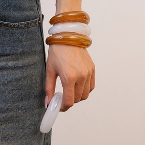 Detailed view of layered amber and cloudy white acrylic resin bangles on a wrist