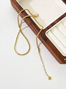 Detail view of gold stainless steel snowflake chain with adjustable lobster clasp on box